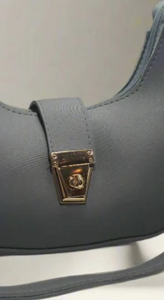 Gray shoulder bag with a gold clasp on a light background