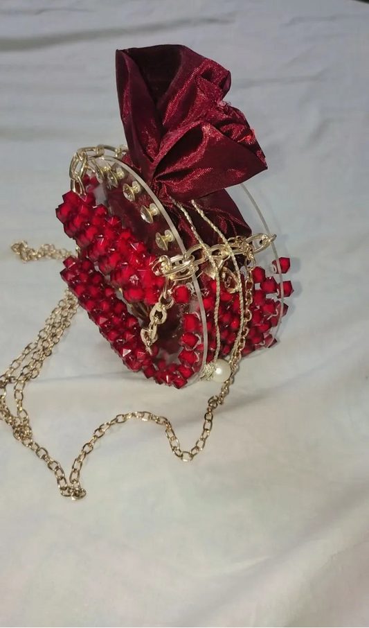 Red heart-shaped bag with gold chain and bow on a white background