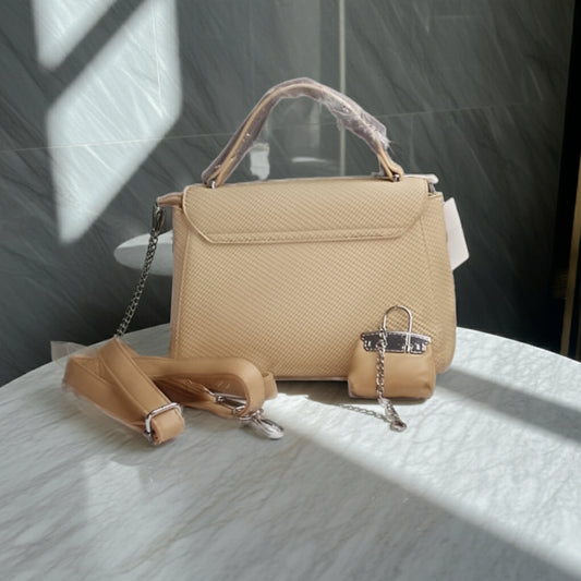 Beige handbag with a detachable strap on a textured surface