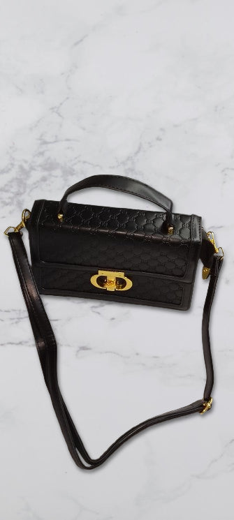 gucci Black handbag with a gold clasp on a light gray marble background