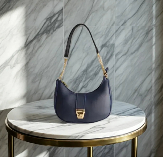 Navy handbag on a round marble table with a marble wall background