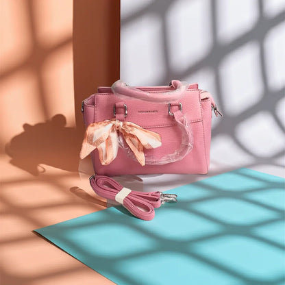 mauve handbag with a matching strap on a light blue surface with shadows.