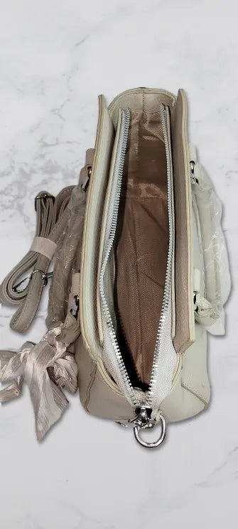 grey handbag with multiple zippers on a light gray background