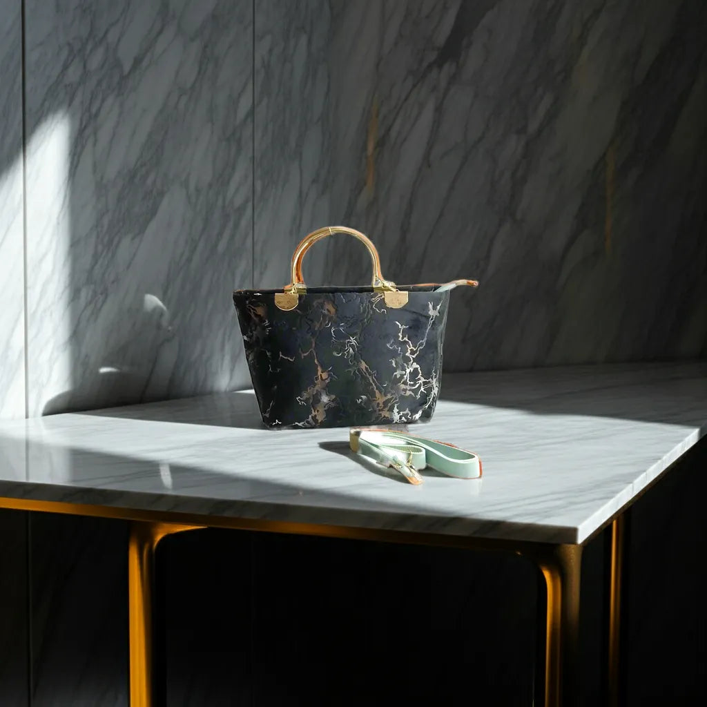 Marble-patterned handbag on a marble surface with a dark marble wall in the background