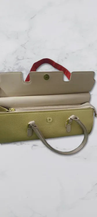 Open beige handbag with a red handle on a light gray background