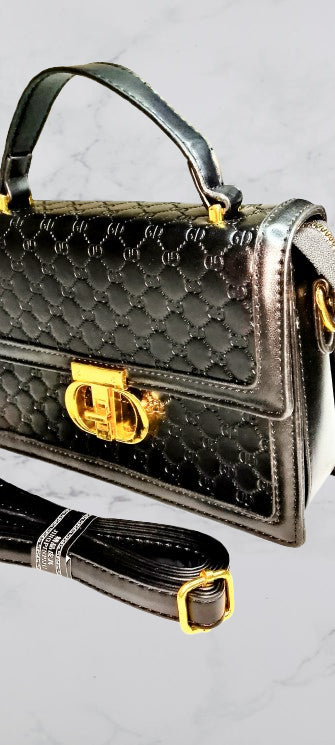 Black quilted handbag with gold accents on a light gray background