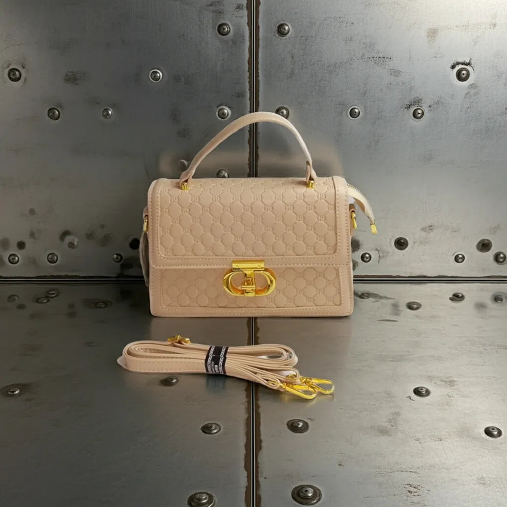 Beige handbag with gold clasp and matching strap on a metallic surface