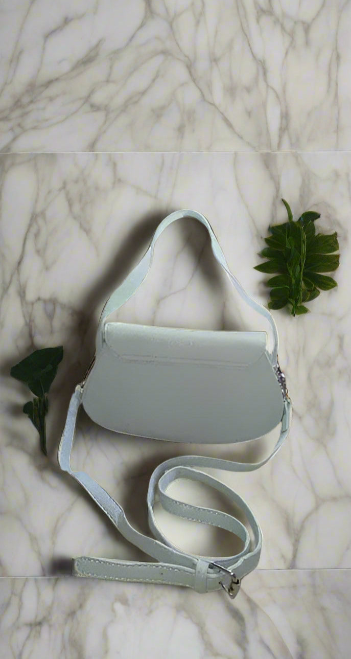 Light gray crossbody bag on a marble surface with green leaves