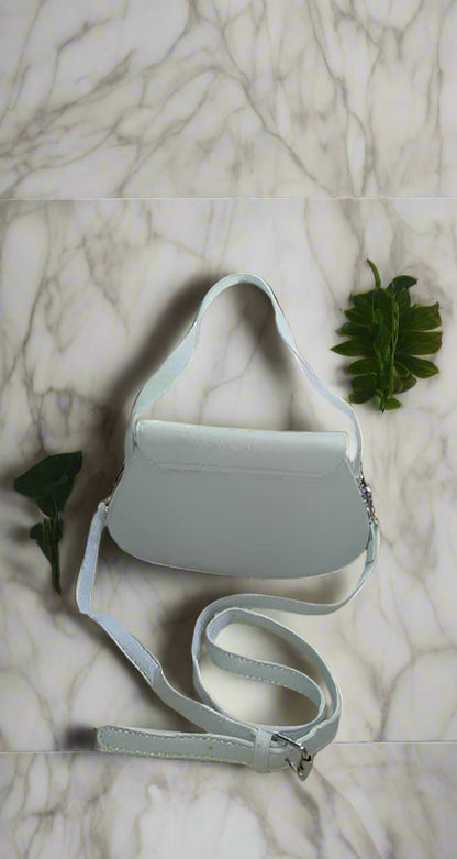 Light gray crossbody bag on a marble surface with green leaves