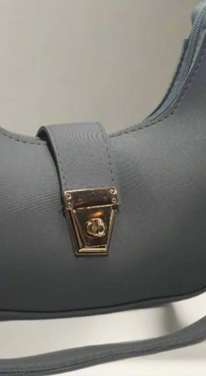 Gray shoulder bag with a gold clasp on a light background