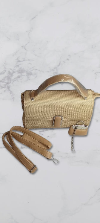 beige handbag with a detachable strap on a light marble background