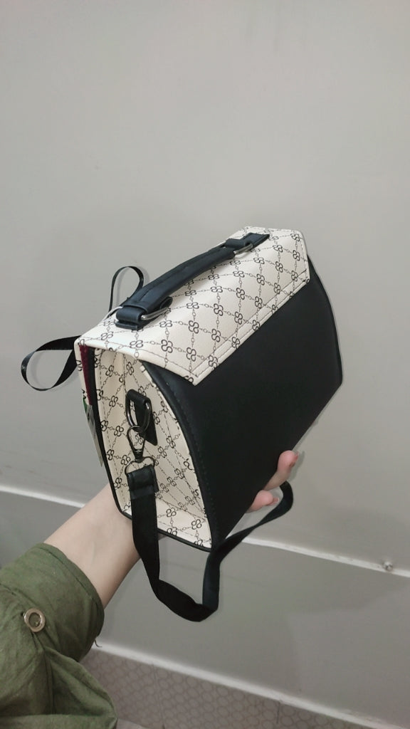 Black and white patterned bag held by a person against a gray background
