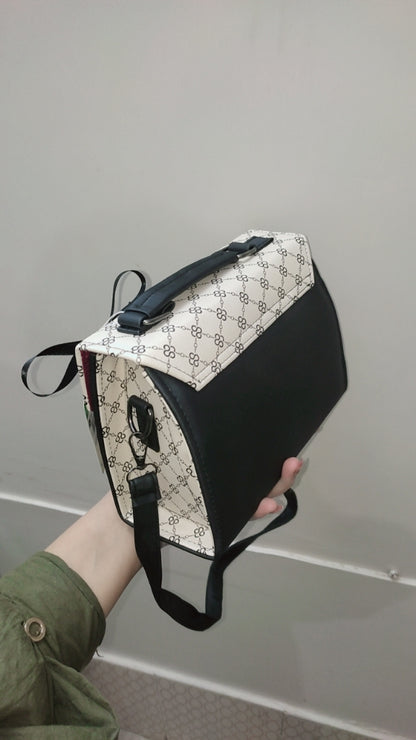 Black and white patterned bag held by a person against a gray background