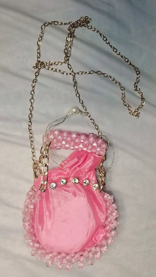 Pink handbag with decorative chain on a light gray background