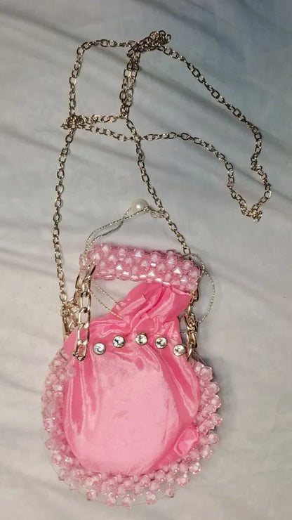 Pink handbag with decorative chain on a light gray background