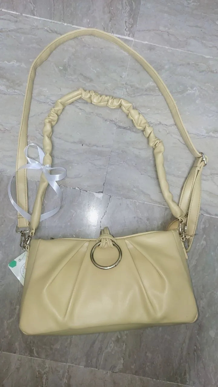 Beige handbag with a strap on a marble surface