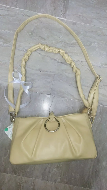 Beige handbag with a strap on a marble surface