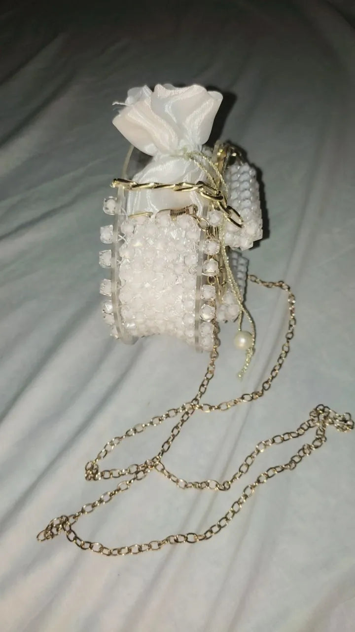 Small white handbag with gold chain strap on a light gray background