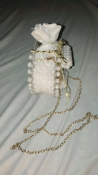 Small white handbag with gold chain strap on a light gray background