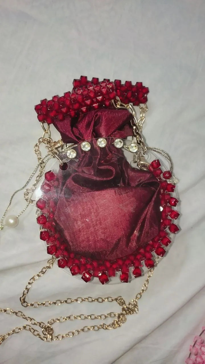 Red velvet handbag with red beads and a gold chain on a light gray background