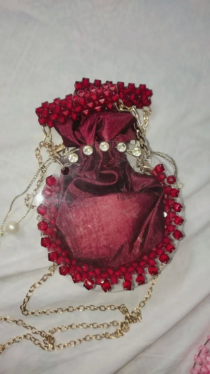 Red velvet handbag with red beads and a gold chain on a light gray background