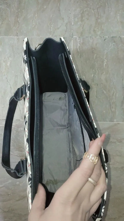 Hand holding a black and white patterned bag against a tiled wall background