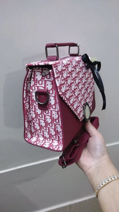 Red handbag with a pattern held by a person against a neutral background