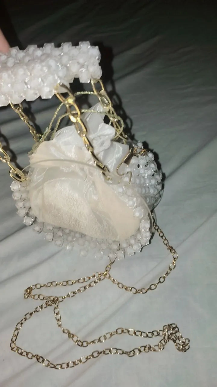 Heart-shaped white pouch with gold chain on a light background