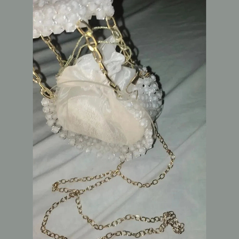 Heart-shaped white pouch with gold chain on a light background