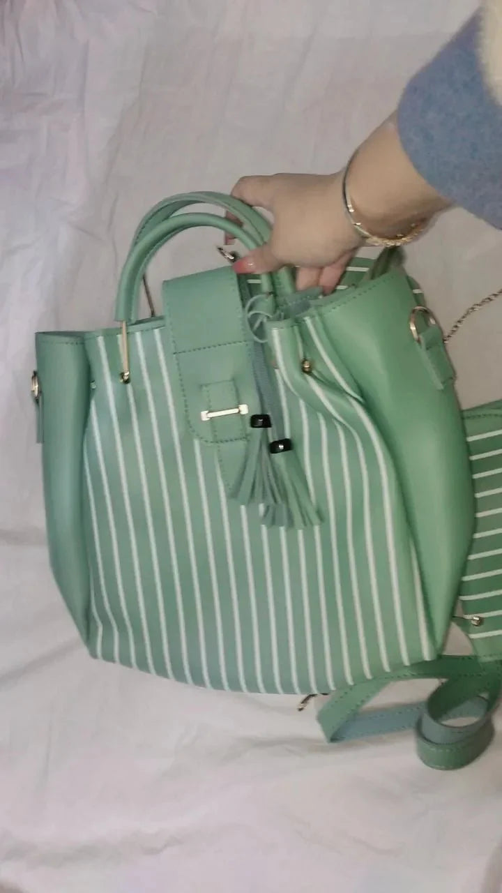 Green striped handbag held by a person on a light pink background
