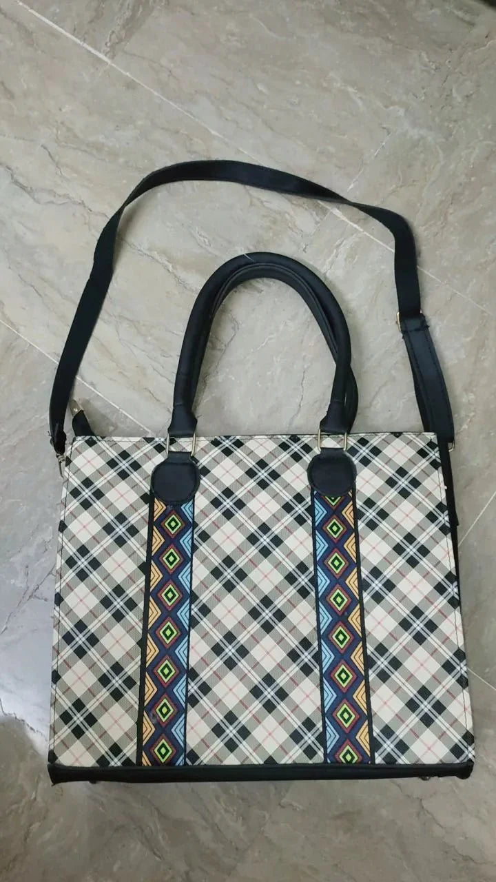 Plaid handbag with decorative straps on a marble surface