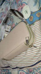 Beige pouch with gold zipper on a patterned fabric background