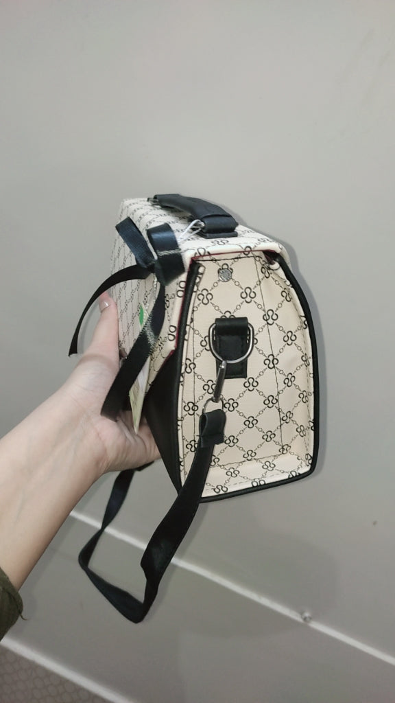 Hand holding a patterned bag against a plain background