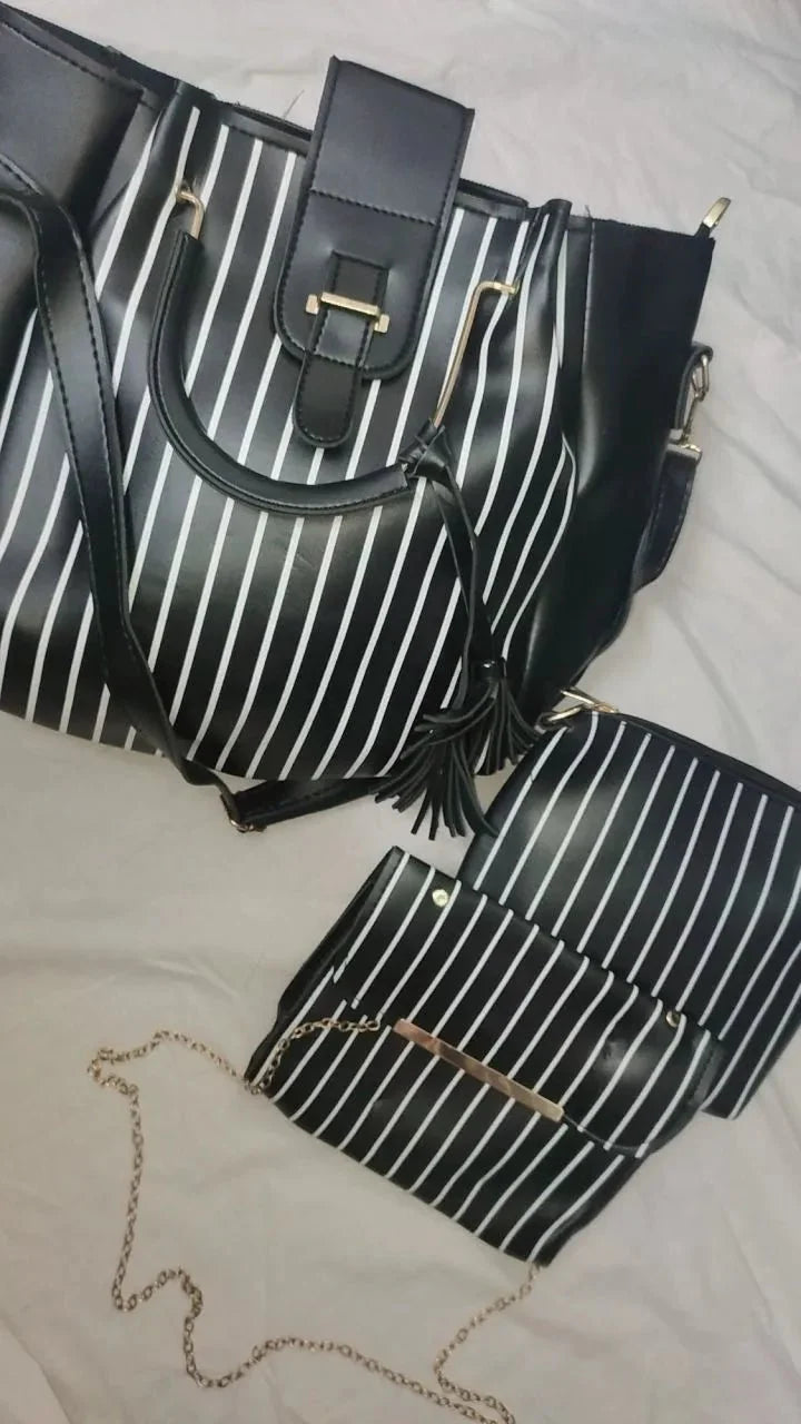 Black and white striped handbag with a smaller matching pouch on a light gray surface