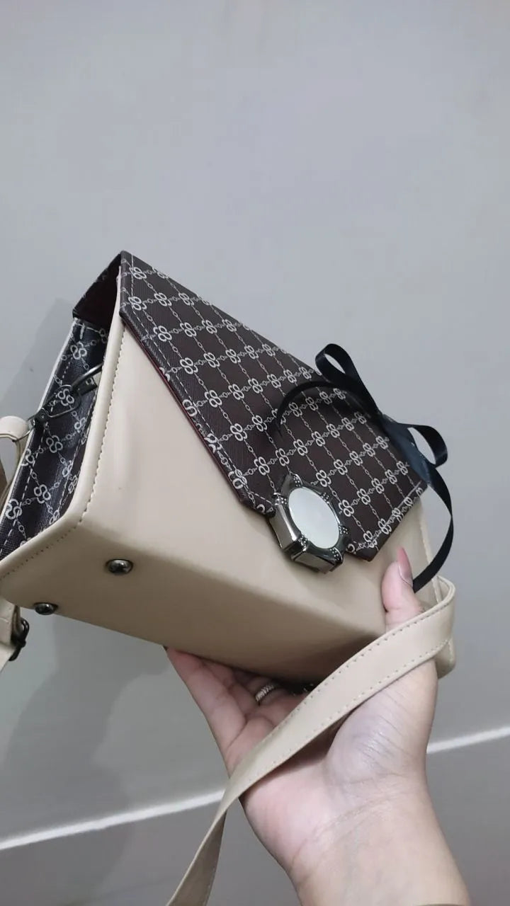 Hand holding a patterned handbag against a neutral background