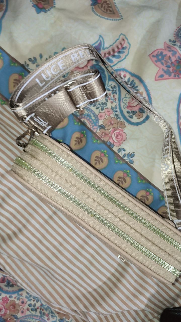 Silver handbag with 'Luce' branding on a floral fabric background