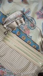 Silver handbag with 'Luce' branding on a floral fabric background