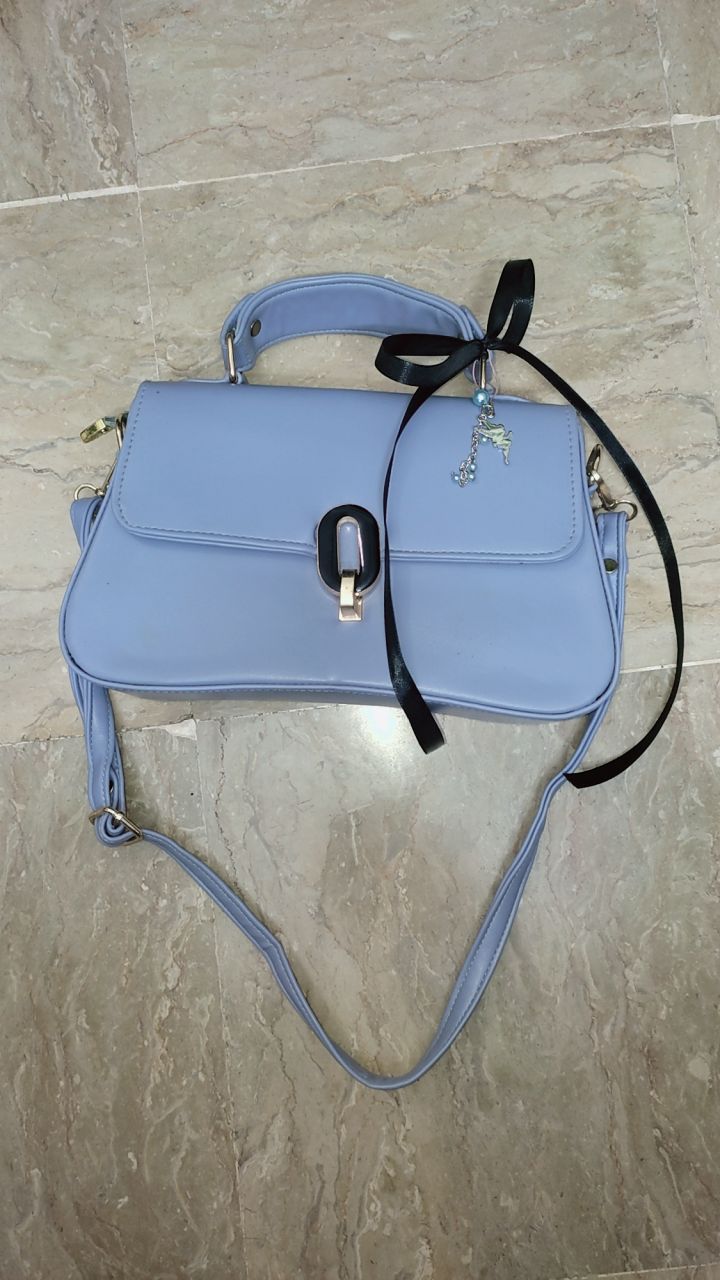 Blue handbag with a black strap on a tiled floor