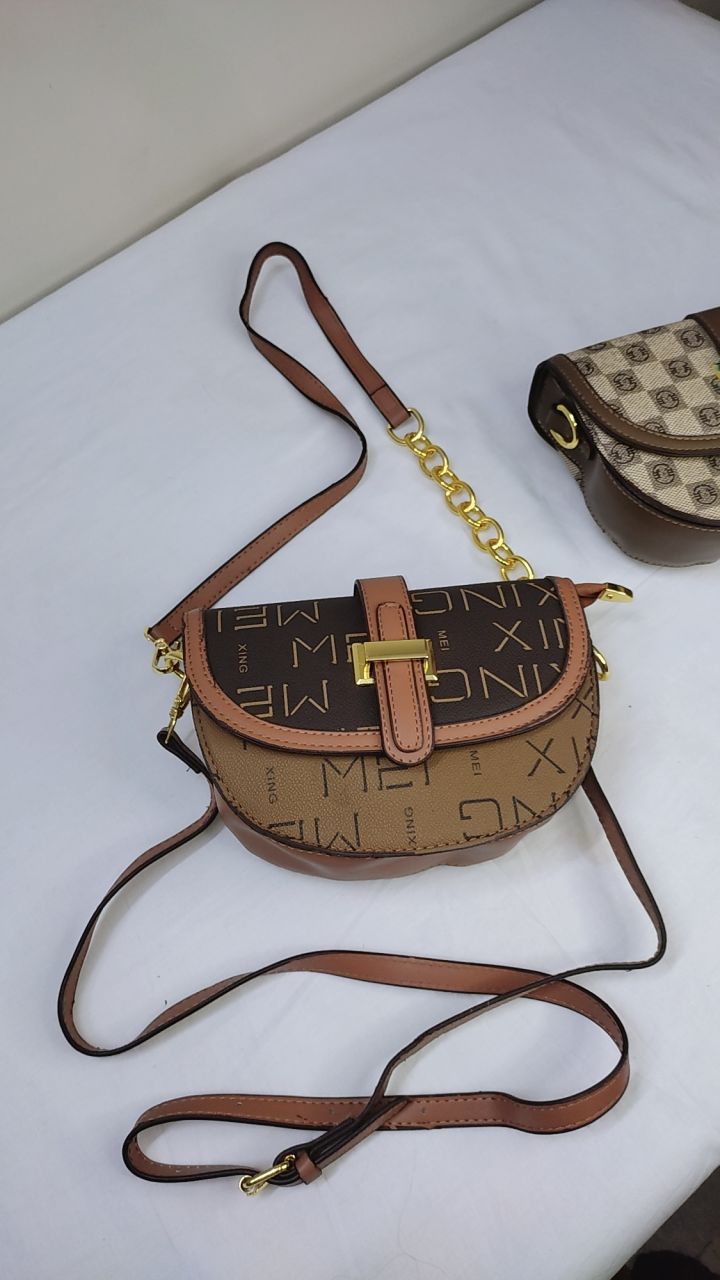 Brown handbag with gold accents held open by a hand, with a visible brand tag.