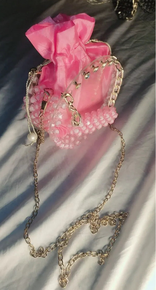 Pink handbag with decorative chain on a textured surface