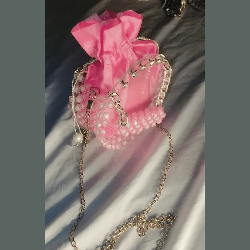 Pink handbag with decorative chain on a textured surface