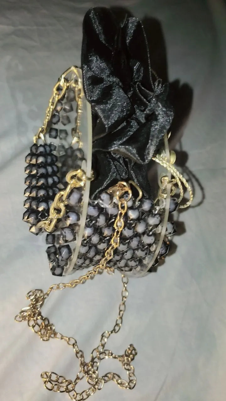 Black glittery pouch with gold chain on a light gray background