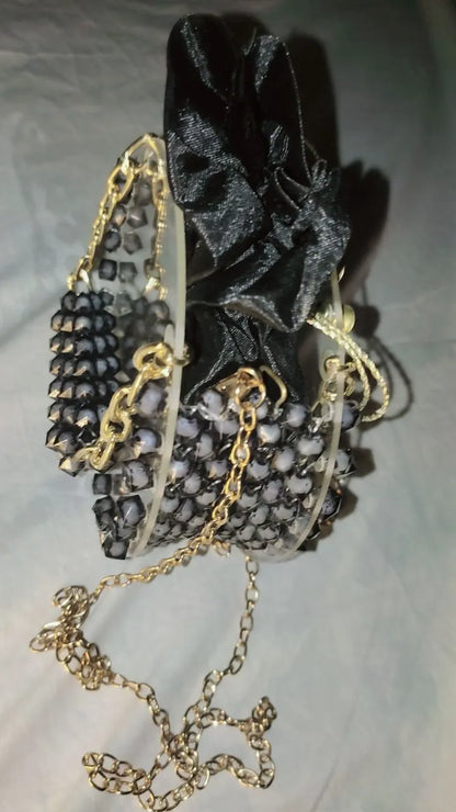 Black glittery pouch with gold chain on a light gray background