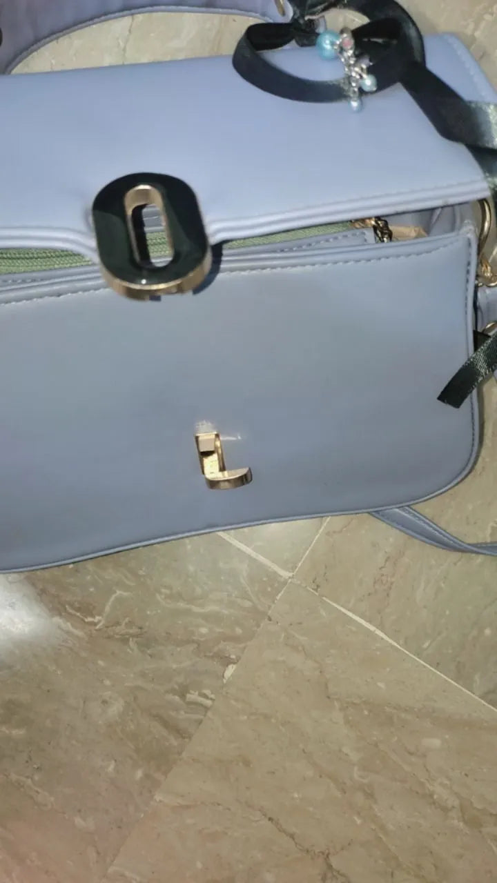 Light blue handbag with gold clasp on a tiled floor