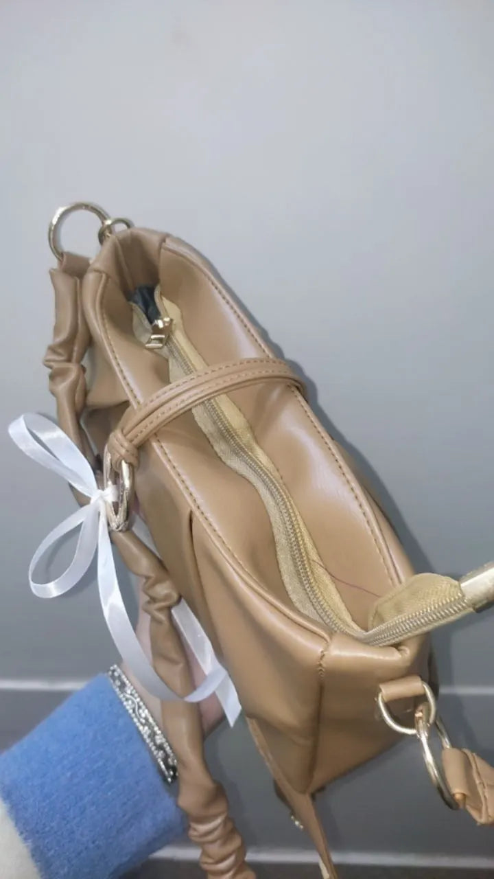 Beige handbag with a white ribbon on a neutral background