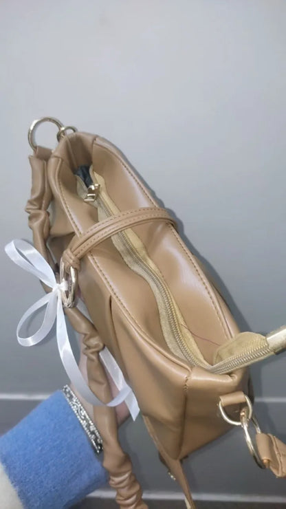 Beige handbag with a white ribbon on a neutral background