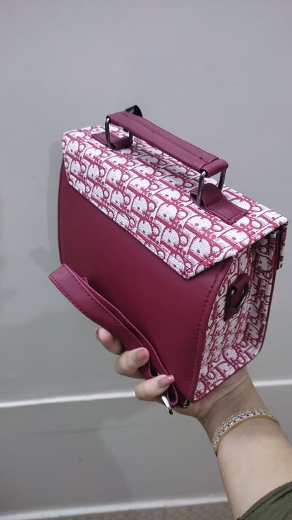 Pink handbag with white pattern held by a person against a neutral background