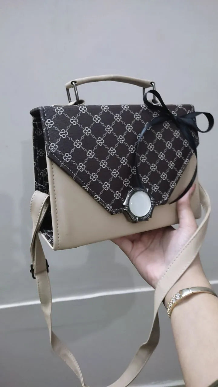 Hand holding a patterned handbag against a neutral background
