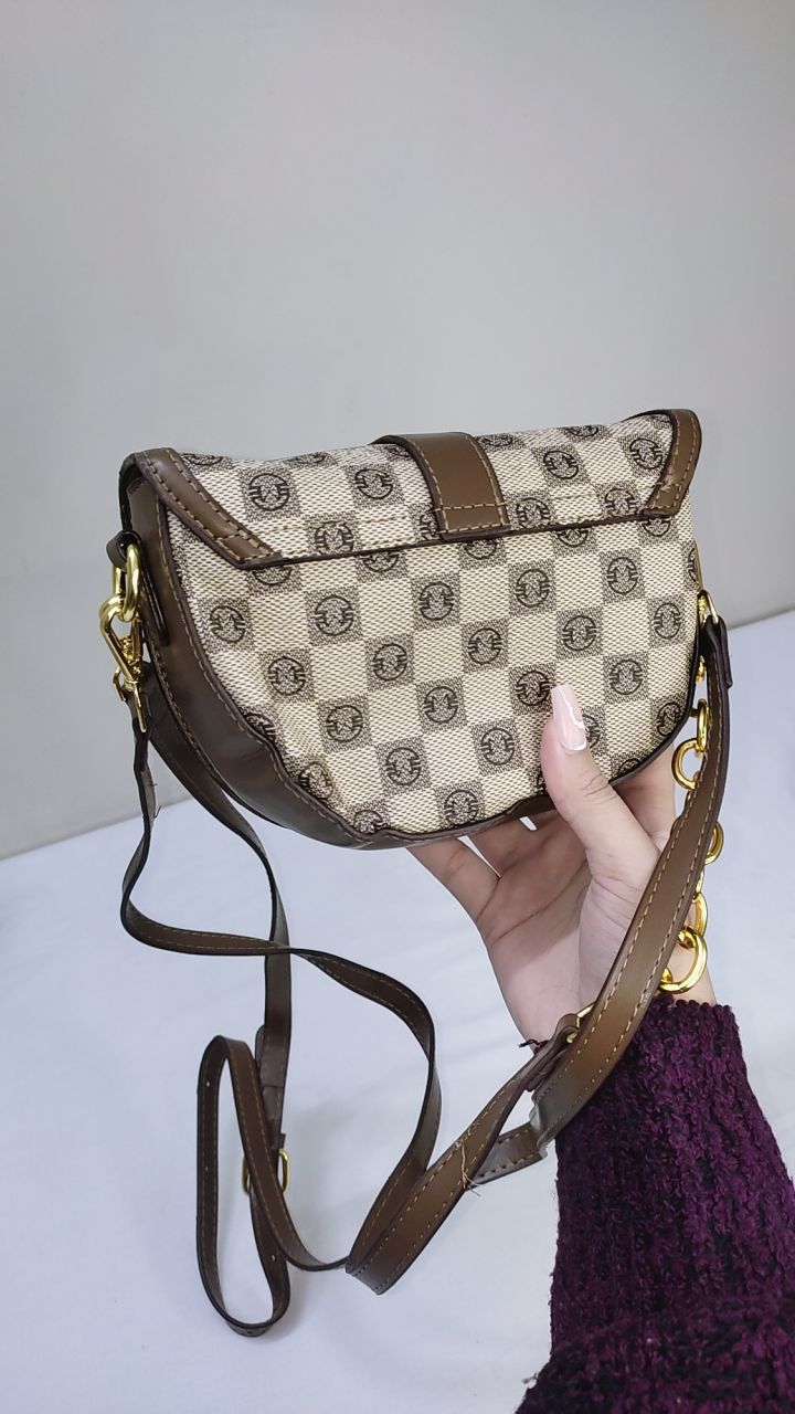 Handbag with a checkered pattern held by a person against a neutral background