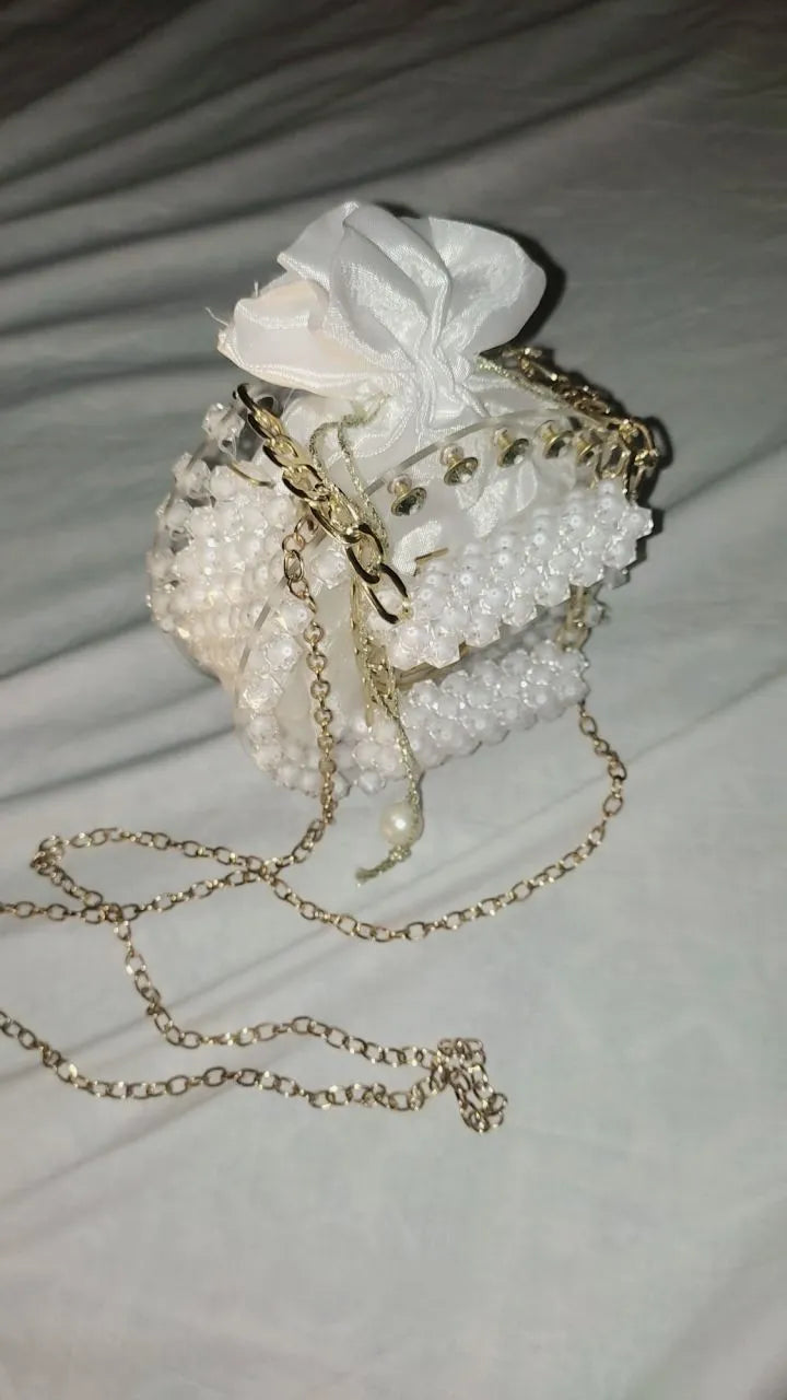 Decorative handbag with pearls and a white flower on a light background
